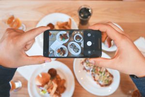 creator filming food on smartphone at restaurant to help video marketing for small business